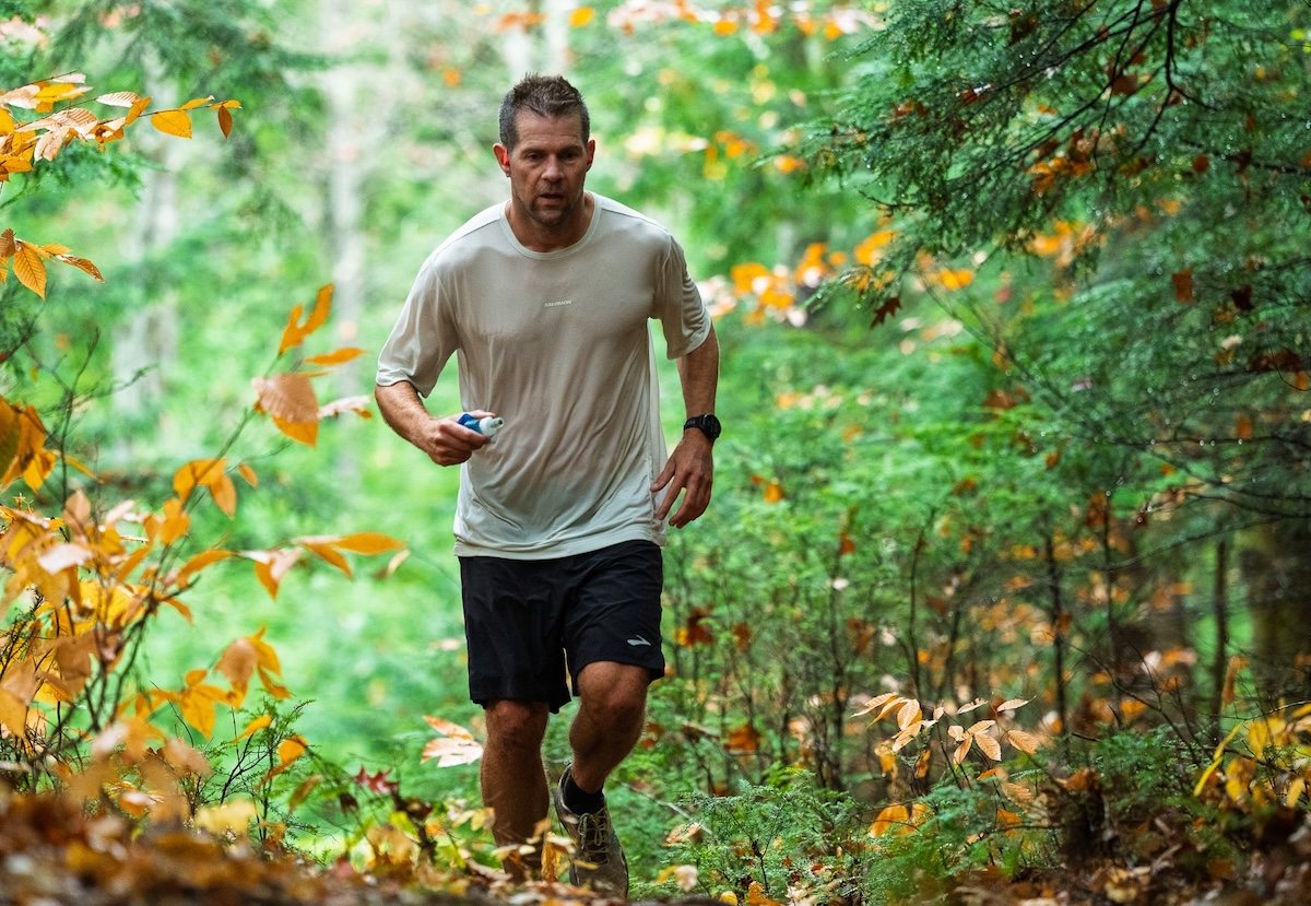 A runner follows a wooded trail